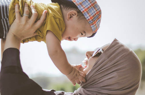 Woman with sunglasses holding baby up